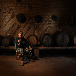 vernaccia wine producer in front of some barrels sipping his own treasure